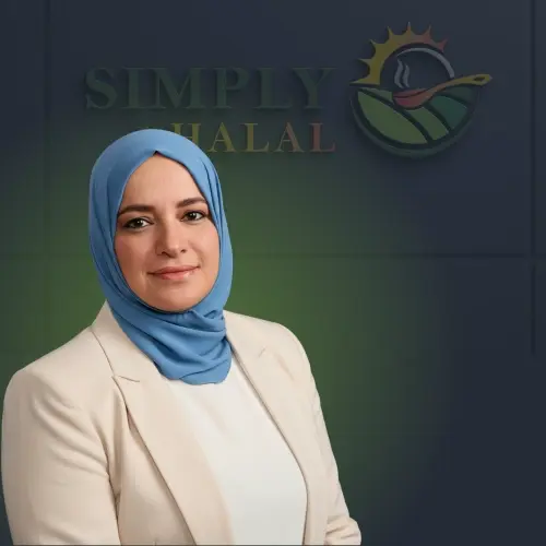Professional portrait of a woman wearing a blue hijab and beige blazer, standing in front of the Simply Halal logo background.