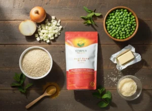 A flat lay of all ingredients needed for Beef Broth Pea Risotto. The Simply Halal Beef Bone Broth powder bag is centered, surrounded by Arborio rice, frozen peas, diced onion, butter, Parmesan cheese, and fresh mint, prepared for the recipe